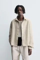 Sobrecamisa de hombre con corte relajado, confeccionada en tejido texturizado jaspeado en tonos beige y negro. Presenta cuello solapa, manga larga con puño de botón y cierre frontal de botonadura.