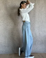 Pantalón de jean azul de tiro medio, con corte wide leg y ruedo deshilachado.