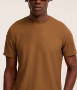 Remera de corte regular con cuello redondo y manga corta, confeccionada en una mezcla de algodón y poliéster con textura tipo colmena.