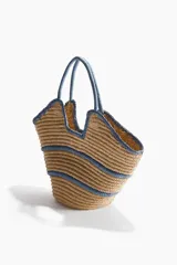 Bolso shopper de doble asa confeccionado en paja de papel trenzada, con diseño estructurado y líneas en tono azul en el cuerpo, asas y bordes.