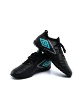 Championes de fútbol Umbro modelo Legacy TF, color negro con detalles en turquesa y gris. Presentan una textura geométrica en el lateral, cuello tipo media para mayor ajuste y suela con tapones pequeños ideales para césped sintético.