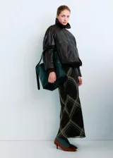 Falda midi de corte al bies con estampado de cuadros escoceses en tonos oscuros, con líneas finas en beige y naranja. Presenta un diseño fluido y ligero.