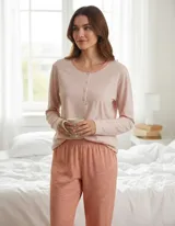 Pijama de dos piezas compuesto por una remera de manga larga con cuello redondo y cierre frontal de botones, y un pantalón de corte recto con cintura elástica. El conjunto presenta un acabado melange en tonos rosados.