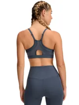 Top deportivo Under Armour Infinity Low 2.0 de sujeción ligera, color gris azulado. Presenta diseño tipo jersey con escote redondo, almohadillas moldeadas integradas y logo de la marca en el frente.