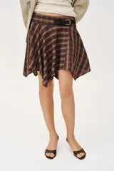 Falda corta de diseño asimétrico con estampado de cuadros en tonos marrones, azules y negros. Presenta una trabilla decorativa en la cintura con hebilla metálica y cierre lateral con cremallera oculta.