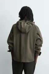 Cazadora relaxed fit de tejido con mezcla de algodón en color verde militar. Cuenta con cuello subido, manga larga con puño ajustable, múltiples bolsillos frontales de plastrón con solapa y cierre frontal con botones.