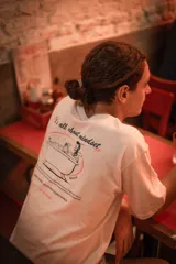 Remera blanca de algodón con estampado en la espalda de una persona en una bañera y la frase "It's all about mindset".