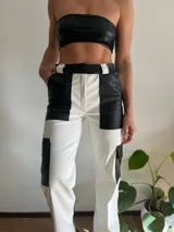 Pantalón de cuero sintético blanco y negro, de corte recto, con bolsillos laterales y traseros.