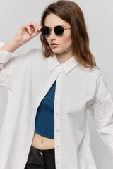 Camisa de algodón blanca de calce relajado, con cuello clásico, mangas largas y cierre frontal con botones.