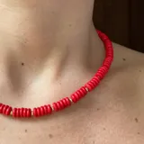 Collar corto de cuentas rojas con detalles dorados.