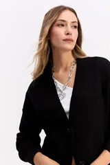 Saco de punto color crema con escote en V, cierre frontal con botones y bolsillos delanteros. Presenta un diseño de calce relajado con estructura marcada.