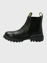 Bota tipo Chelsea de la marca Hush Puppies, confeccionada en cuero negro con paneles laterales elásticos y tiradores superiores con diseño gráfico en amarillo y negro. Presenta una suela de goma robusta y dentada con tecnología Fusion para mayor absorción de impactos.