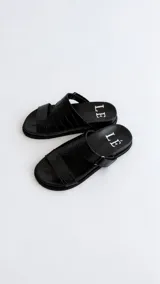 Sandalias de cuero color marrón con diseño asimétrico de tiras y plantilla anatómica. Tienen ajuste lateral con velcro y suela plana.