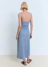 Vestido midi de corte recto con diseño estilo vaquero, confeccionado en una mezcla de algodón y lino. Presenta un escote cuadrado, tirantes finos ajustables y un detalle drapeado en uno de los laterales de la cintura. Cuenta con cierre de cremallera lateral.