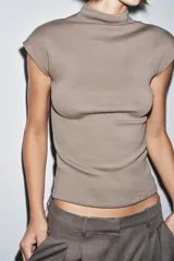 Top negro de tejido de punto, corte ajustado, con cuello alto y mangas sisa caídas.