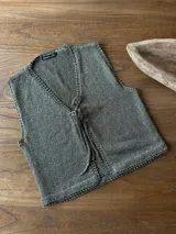 Chaleco de tejido de punto en color verde militar, con escote en V y cierre frontal con tiras para anudar.