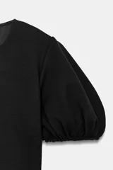 Top de algodón color negro con cuello redondo y mangas cortas abullonadas con terminación elástica.