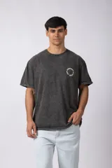 Remera oversize de algodón con efecto lavado gastado, cuello redondo y mangas cortas. Presenta un diseño circular estampado en el pecho con el texto VCP CONCEPT STUDIO.