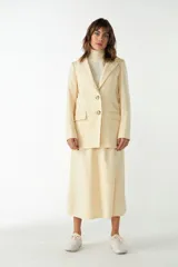 Blazer largo color crema con cuello solapa, bolsillos con solapa y forro interior combinado a tono. Confeccionado en lana fina sin teñir.