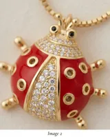 Cadena de eslabones finos con baño de oro y dije en forma de mariquita esmaltada en color rojo, con detalles de circonias incrustadas.