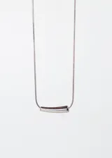 Collar plateado con cadena fina y dije horizontal en forma de barra ovalada.