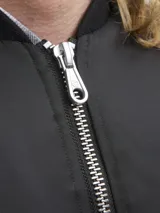 Campera bomber liviana de nylon color negro, con cuello estilo baseball, cierre frontal de doble dirección y puños acanalados.