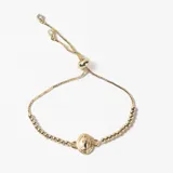 Pulsera ajustable de cadena fina con cuentas metálicas y dije central ovalado con imagen religiosa. Cuenta con un sistema de cierre deslizante terminado en dos pequeñas piedras brillantes.