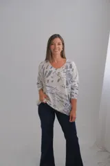 Sweter de punto con corte amplio, escote en V y mangas largas. Presenta un diseño estampado abstracto sobre una base color crudo con detalles en tono dorado.