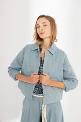 Chaqueta capitoneada celeste vintage de denim de algodón 100% natural pre-lavado y suavizado, con bolsillos laterales, botones a presión escondidos y ruedo curvo en los costados.