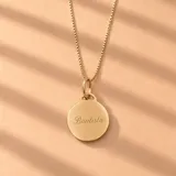 Collar de oro 18k con cadena de eslabones finos y dije redondo grabado con la inscripción 'Mi primera comunión' y fecha.