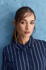 Camisa de calce relajado con cuello clásico, mangas largas con puños elastizados y rayas verticales que aportan un estilo atemporal. Su diseño liviano y versátil cuenta con estampado floral verde sobre fondo de rayas celestes y blancas.