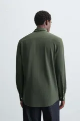 Camisa de manga larga color celeste claro, corte slim fit, con cuello italiano abierto y cierre frontal de botonadura.