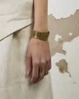 Brazalete rígido de diseño orgánico con textura irregular y acabado artesanal. Pieza abierta ajustable, disponible en bronce o alpaca maciza.