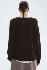 Buzo de punto fino color marrón oscuro, de corte holgado con escote redondo y mangas raglán. Presenta puños y bajo acanalados.