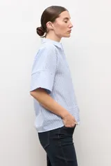 Camisa celeste con rayas blancas, de manga corta y cuello camisero.