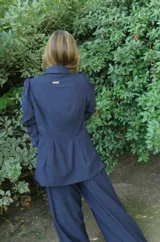 Blazer rojo de seda con cuello solapa, hombreras marcadas y un botón decorativo en forma de sol.