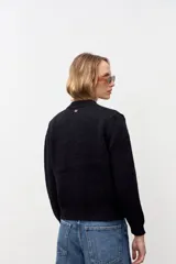 Cardigan de punto negro con sutiles destellos brillantes, cuello redondo, cierre frontal con botones y puños acanalados.