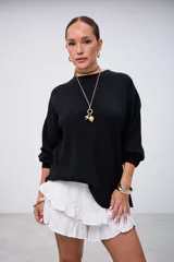 Sweater negro de punto con cuello redondo, mangas largas y corte holgado.