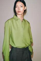 Camisa oversize de popelín de algodón color verde claro, con cuello solapa y manga larga. Cierre frontal con botones ocultos y bajo redondeado.
