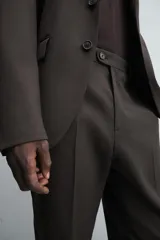 Pantalón de traje regular fit confeccionado en tejido de lana. Presenta bolsillos frontales, bolsillos traseros de vivo con botón y cierre frontal con cremallera y botón.