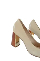 Zapatos de tacón color beige con punta fina y tacón geométrico que combina madera clara con detalles dorados.