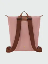 Mochila de diseño minimalista en color beige, con solapa y asa superior en cuero marrón texturizado. Cuenta con correas ajustables en color marrón y cierre principal.