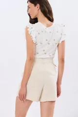 Short de viscolino color beige, con media cintura elastizada, bolsillos amplios y detalle de volado en los laterales.