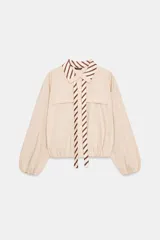 Camisa o cuerpo de manga larga color beige claro, con cuello solapa a contraste con estampado de rayas marrones y blancas. Presenta lazada a juego, bolsillos con solapa en el delantero y bajo con elástico.
