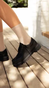 Zapato acordonado de cuero negro con suela track.