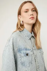 Campera cropped de denim celeste con tachas plateadas formando el logo de la marca.