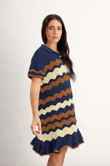 Vestido corto de punto con patrón en zigzag de franjas azules, marrones y amarillas, cuello polo con cierre frontal de un botón, mangas cortas y volado en el ruedo.