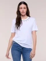 Remera blanca de calce recto y cuello redondo, confeccionada en suave jersey con detalle de aplicación de piedras brillantes a modo de gargantilla en el escote.