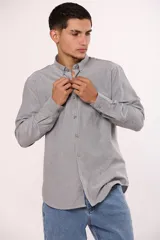 Camisa de manga larga en color gris, confeccionada en algodón, con cuello abotonado y cierre frontal de botones.