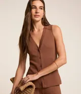 Blusa estilo chaleco marrón, confeccionada en tejido acanalado de viscosa con elastano, escote en V y cierre frontal de botones.